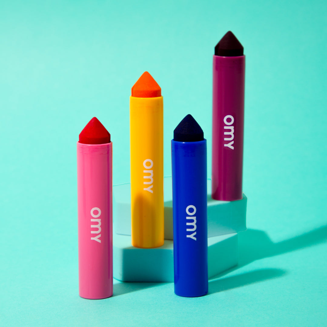 Four OMY colorful lip crayons on a turquoise background
