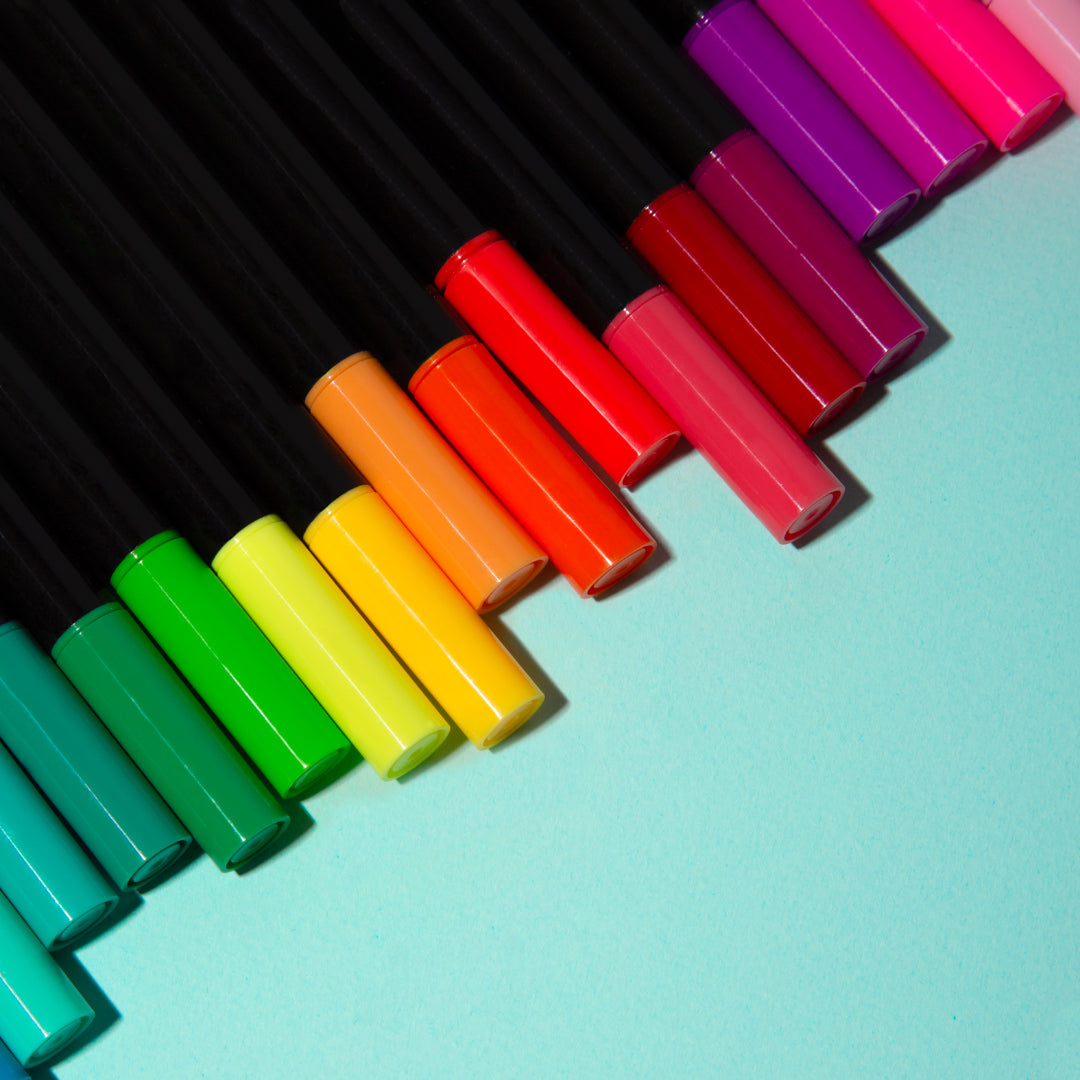 OMY colorful markers arranged in a diagonal pattern on a light blue background