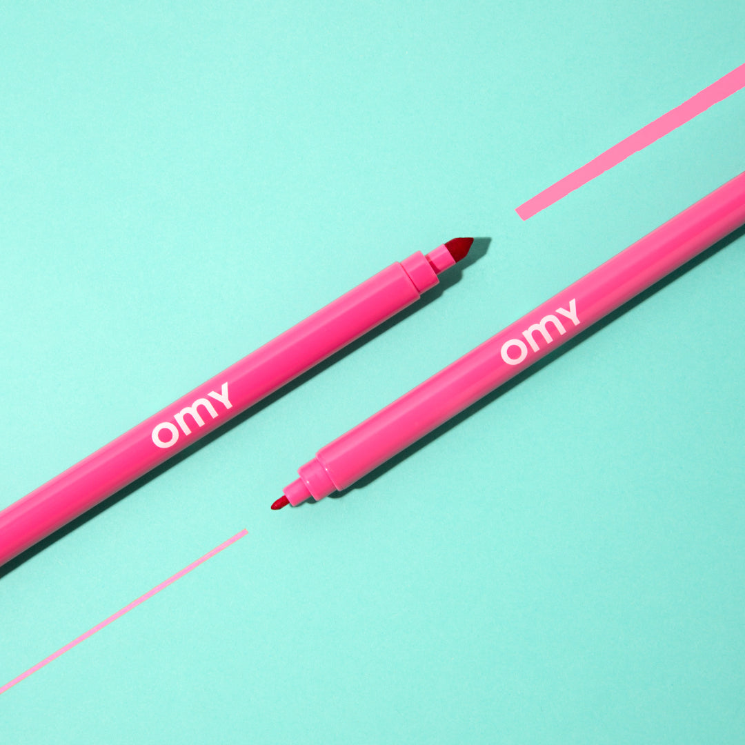 Two pink markers with 'omy' branding on a light blue background