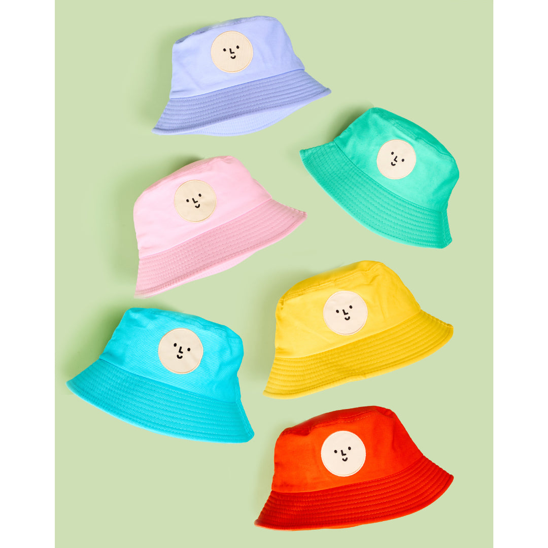 Set of colorful bucket hats with smiley face designs on a light green background