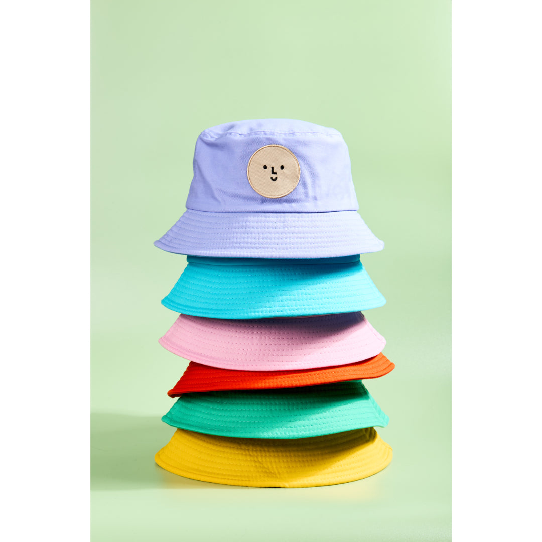Stack of colorful bucket hats on a light green background