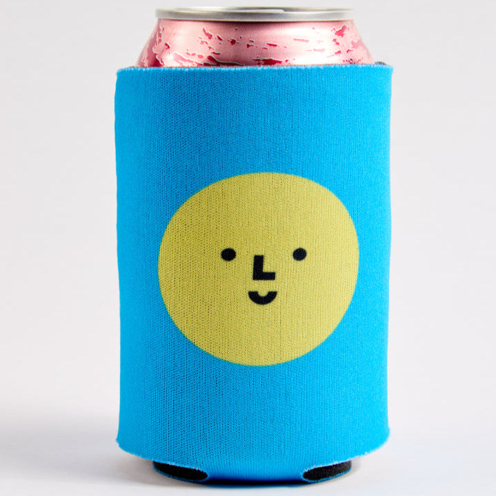 Blue can cooler with a yellow circle and smiley face design on a white background