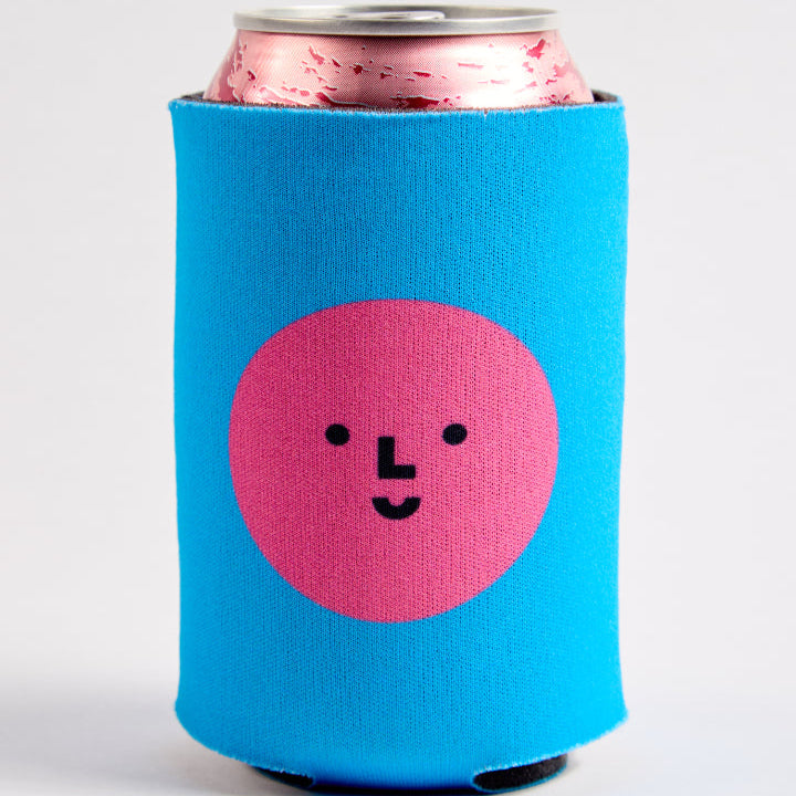 Blue can cooler with a pink circular design featuring a face on a white background