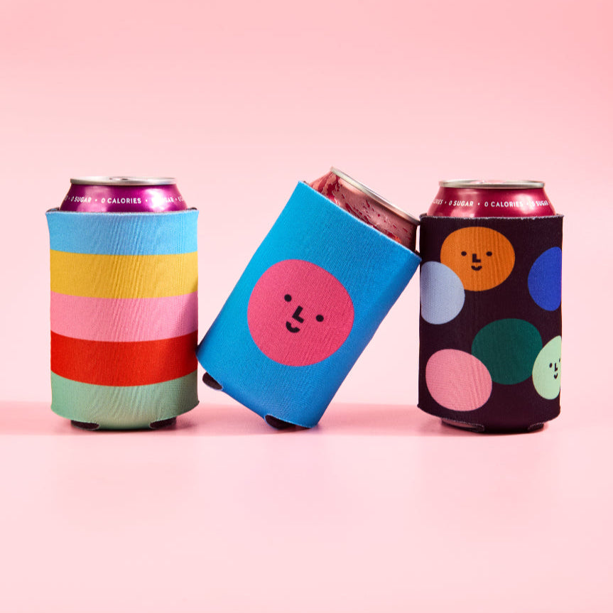 Three colorful can coolers on a pink background