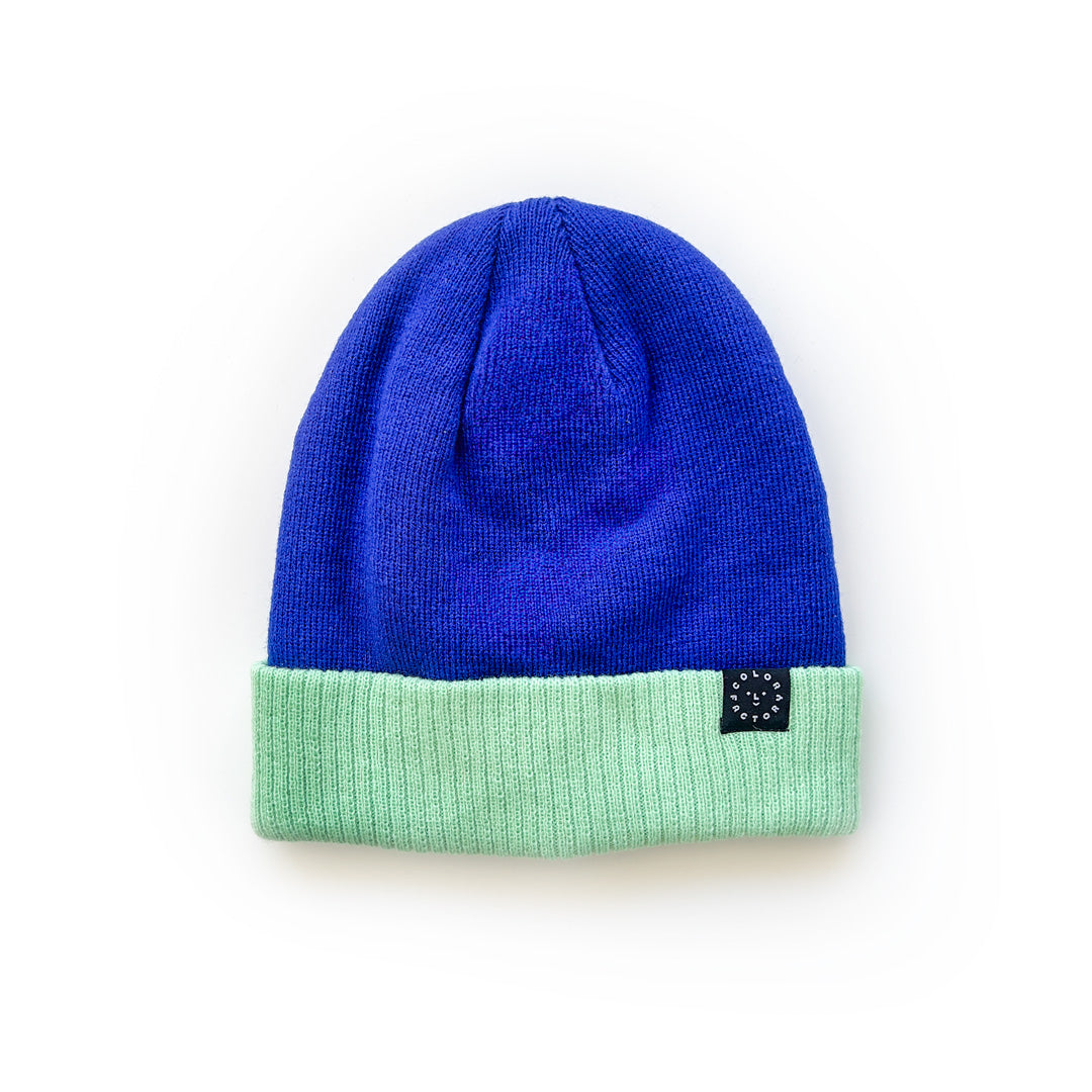 A blue beanie with a green folded brim, displayed on a white background.