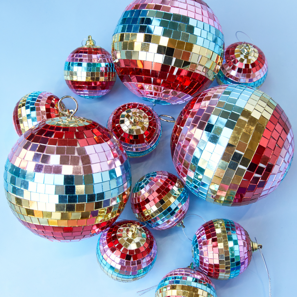 a pile of rainbow striped disco balls on a light blue backdrop